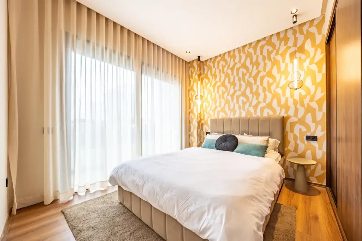 Bedroom with warm graphic wallpaper and floor-to-ceiling curtains